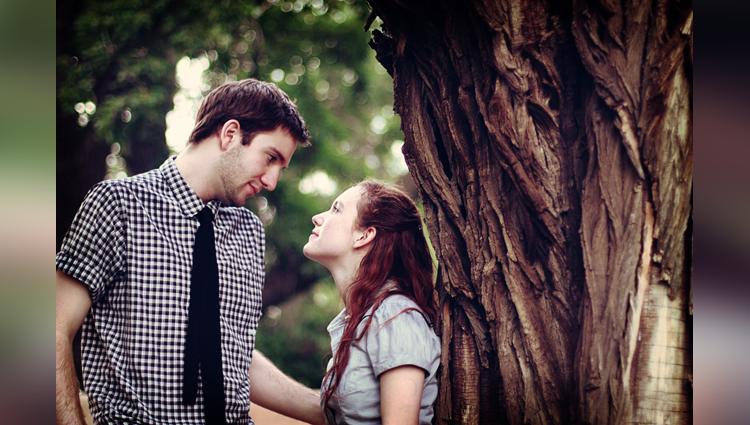 Hiding their love from the world behind a tree