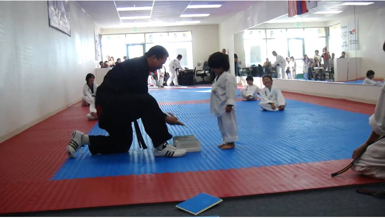 little boy trying to break board in taekwondo 