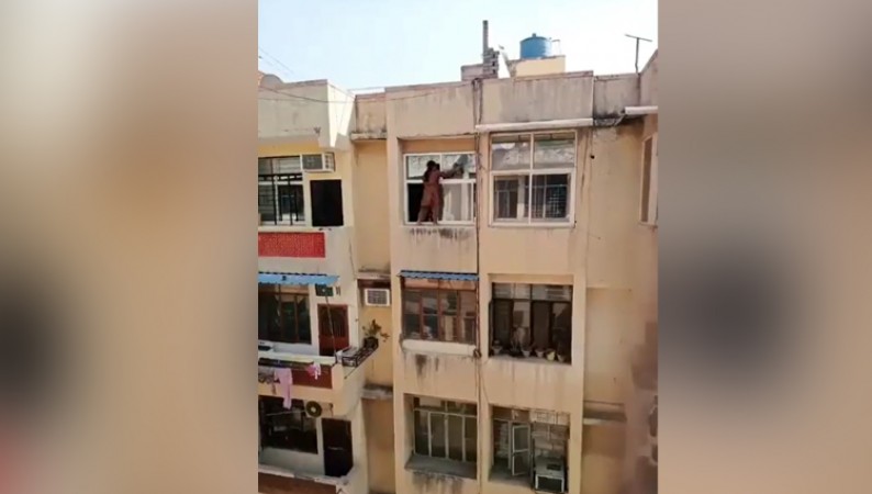 woman dangerously cleaning the windows of a house while standing on ledge video viral on social media